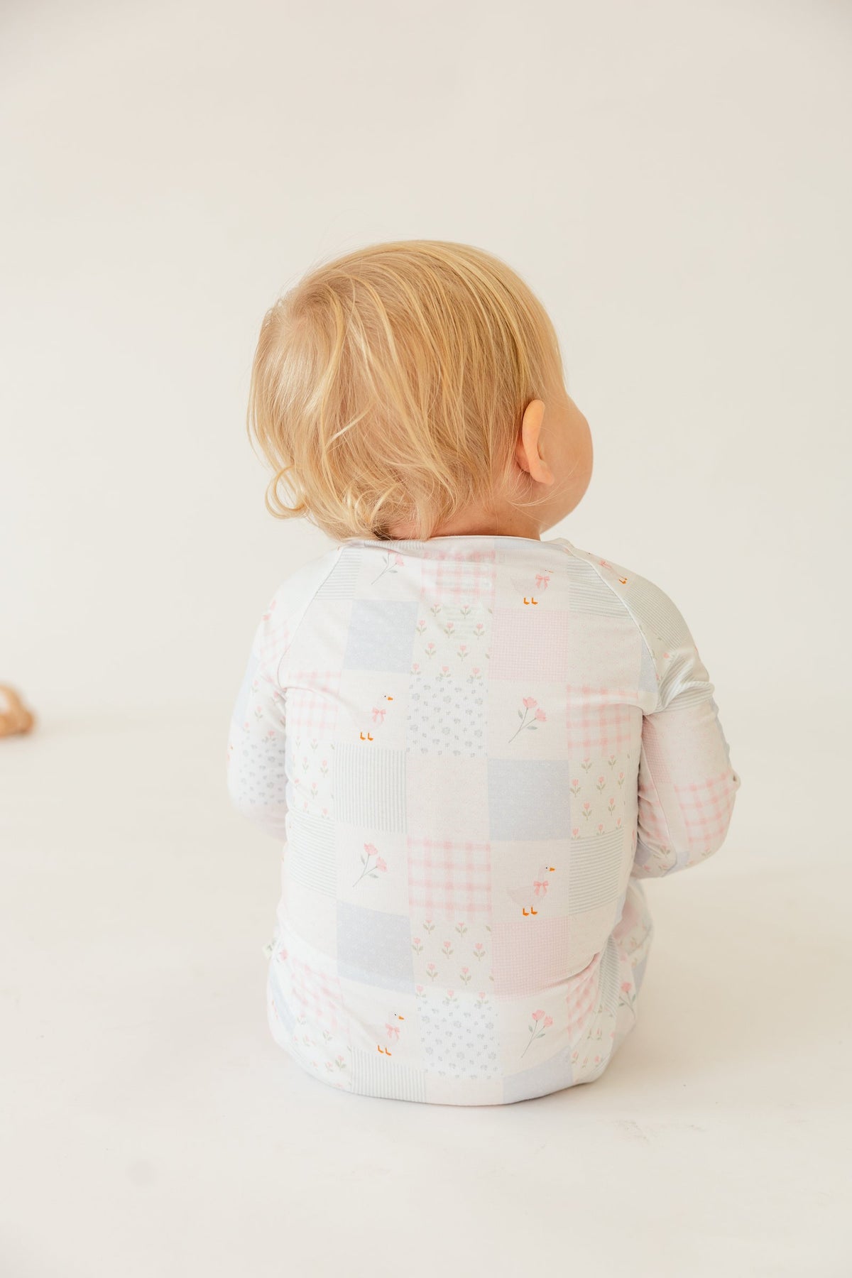 Back view of the Heirloom Quilt sleeper on a seated toddler