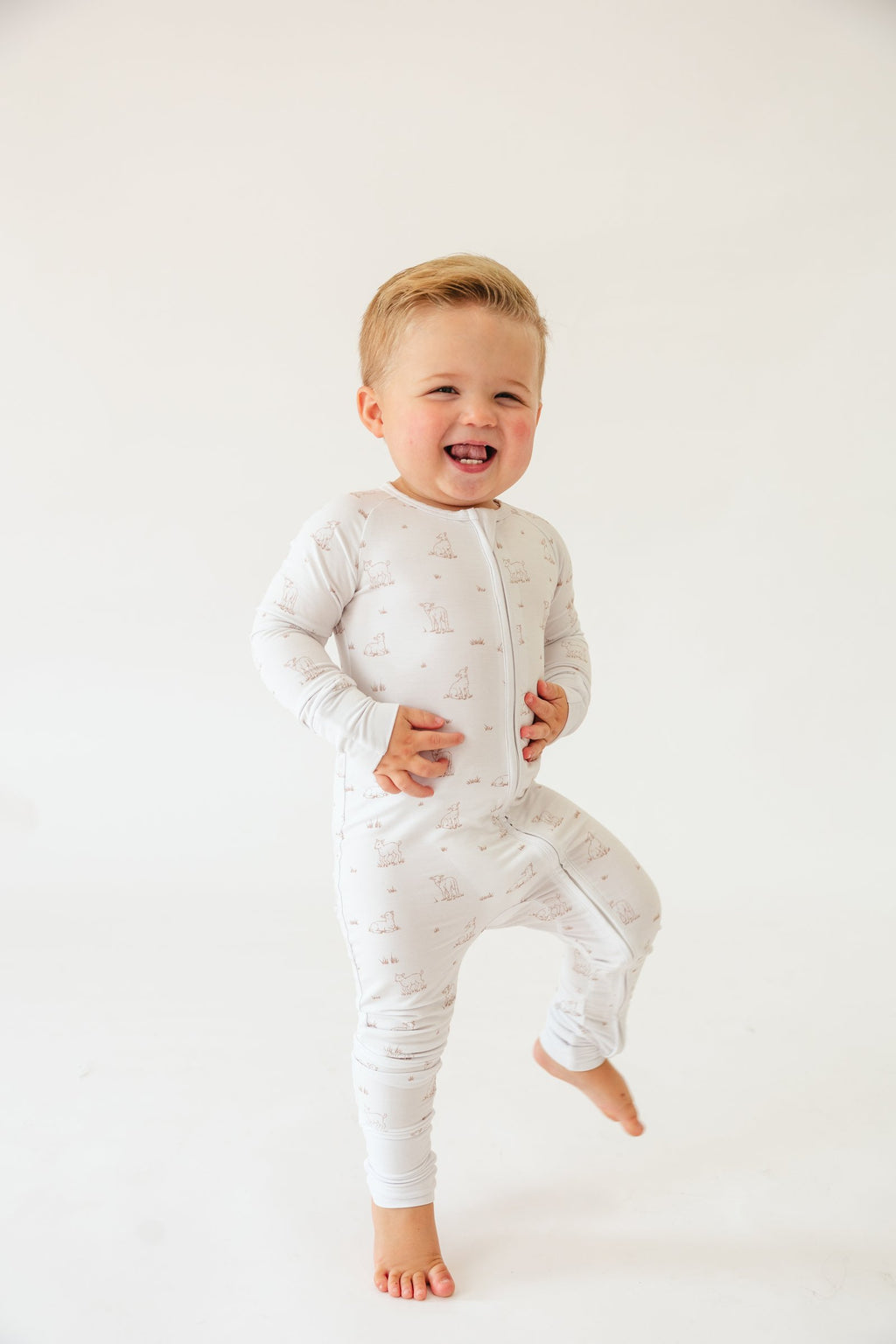 Laughing toddler standing in the Little Lamb bamboo sleeper