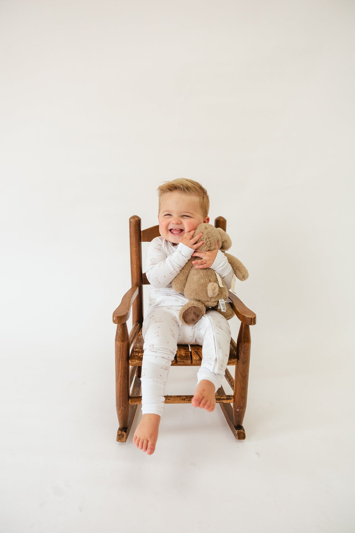 Toddler hugging a teddy bear in a rocking chair