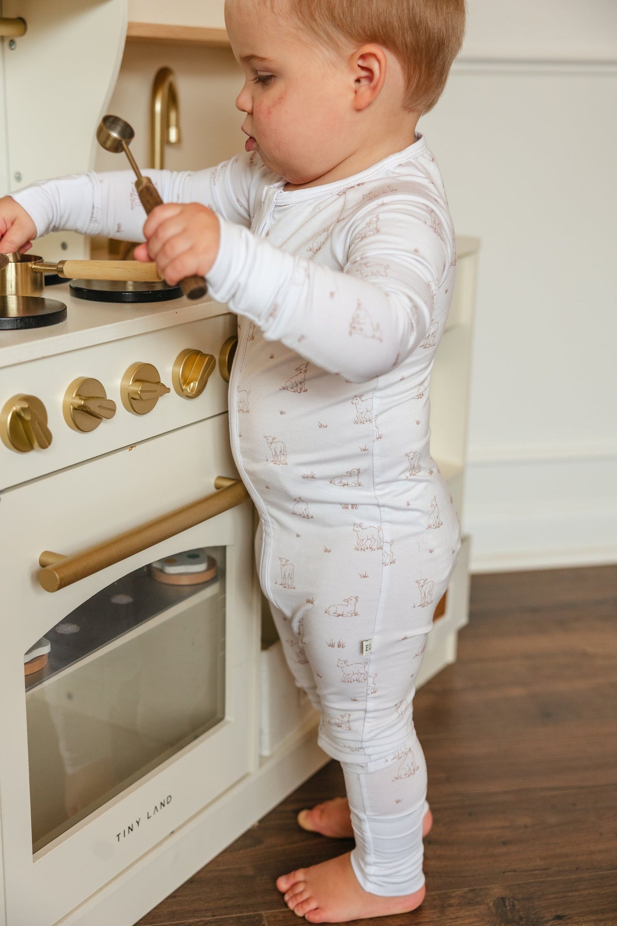 Toddler playing at a toy kitchen in the Little Lamb sleeper